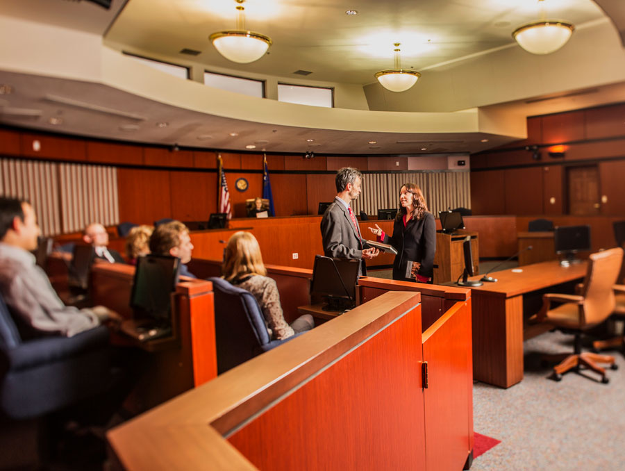 Two people standing in front of a jury box and talking to each other in a courtroom