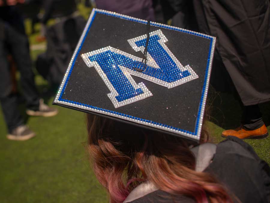 A graduation cap, seen behind, with a decorated N on it.