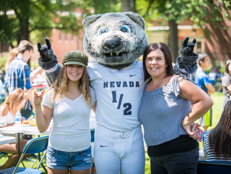 Wolfie and two individuals on the lawn at a welcome BBQ