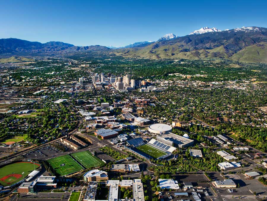 A view from the north of campus, including the athletic fields, and the city of Reno, with snow-capped mountains in the background. 
