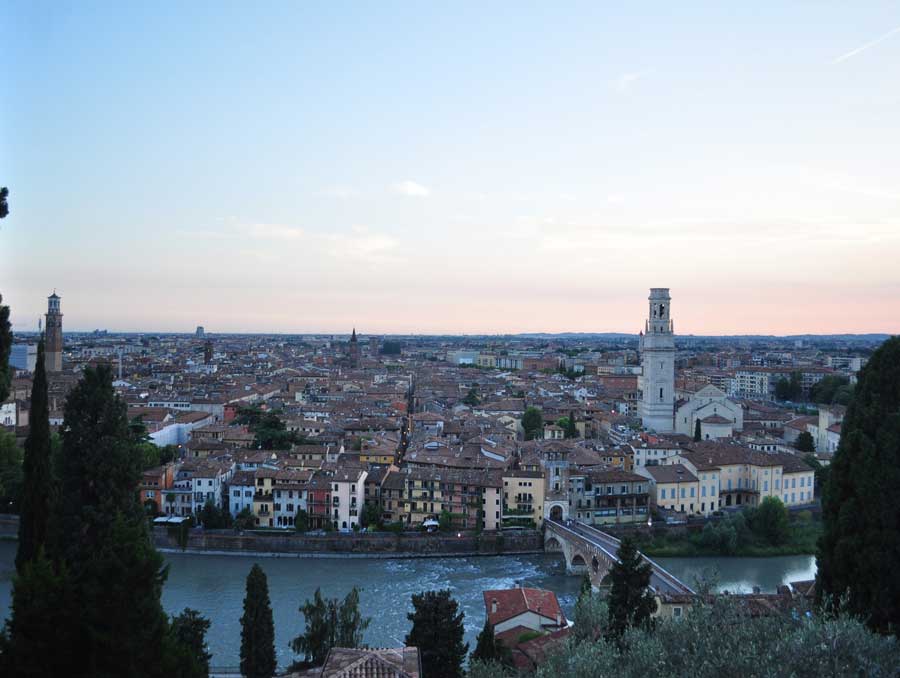 The skyline of Verona, Italy at sunset, with a river shown in front of the old city