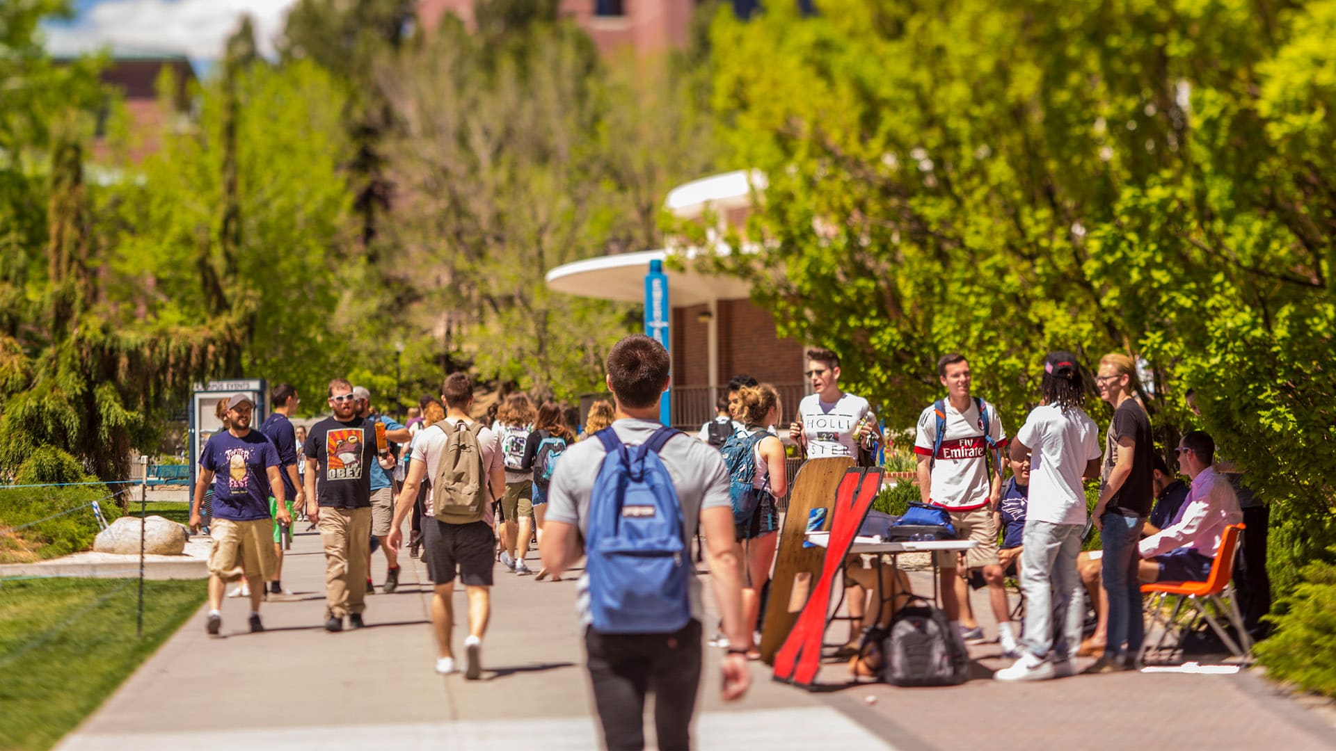 A busy campus scene on the lower quad, with students walking to and from classes and tabling. 