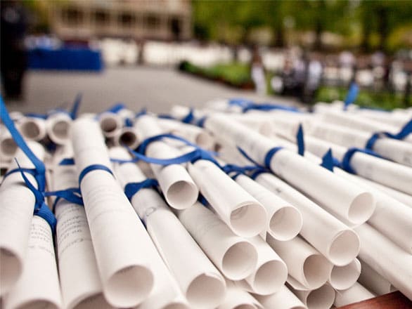 A stack of white diplomas, each wrapped with a blue ribbon, sits on a table on the Quad at the University of Nevada, Reno campus.