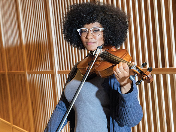 A violinist poses with a violin on her shoulder