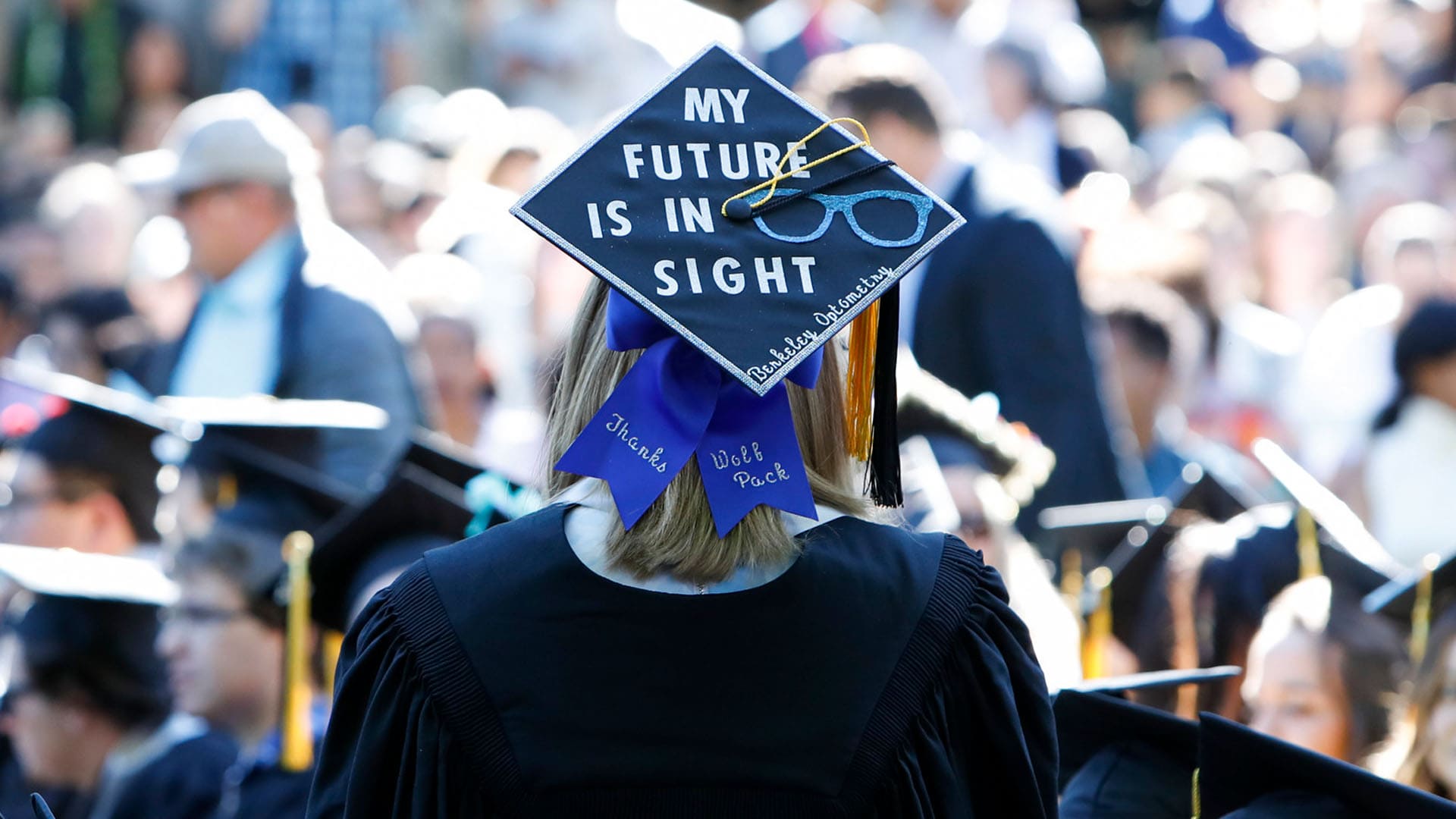 A student wearing a mortar board with the words "My future is in sight" stands among a crowd of graduating students.