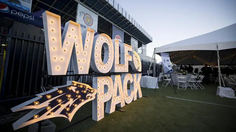 A Wolf Pack sign made of lights is next to a sign of the Nevada Wolf Pack Sport Wolf logo also made of lights, at a Nevada Alumni Association event.