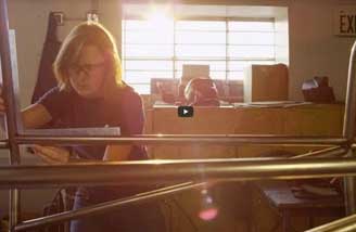 A student in an engineering lab working on a project; sunlight is streaming into the lab from a window behind the student