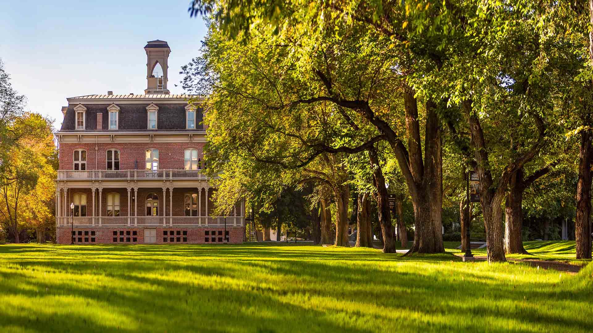 Morrill Hall sits on the south end of the University of Nevada, Reno quad, a large lawn area surrounded by trees and a walking path.