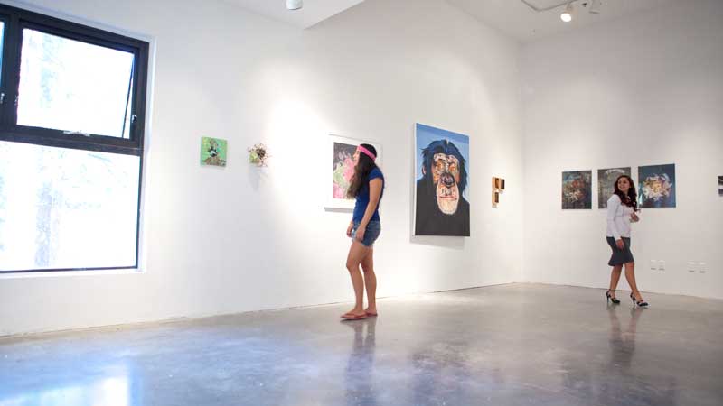Individuals look at art in a gallery exhibition space