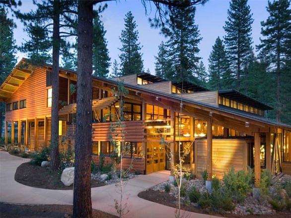 Prim Library at the University of Nevada, Reno Lake Tahoe campus — a modern wood-and-glass building surrounded by tall pine trees, warmly lit at dusk.