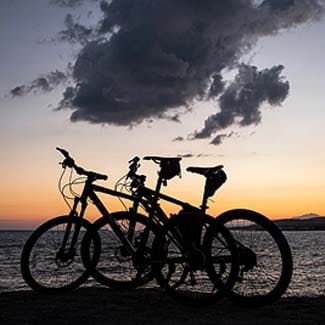 Silhouette of two bicycles parked on a pier at sunset with Lake Tahoe in the background.