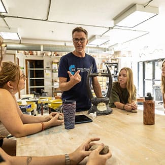 Professor leading a hands-on lesson with students around a large table in a bright classroom at University of Nevada, Reno at Lake Tahoe.