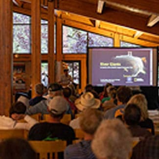 Audience seated inside Prim Library at University of Nevada, Reno at Lake Tahoe, watching a presentation on a large screen during a Tahoe Series lecture.