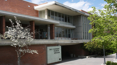 An exterior of the Fleischmann Agriculture Building, an older brick building with trees in front and a large plaque with the words "Fleischmann Agriculture Building."