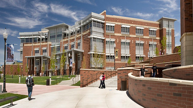 Exterior of the Joe Crowley Student Union, a modern brick building with large windows, concrete pathways and large grass lawns.