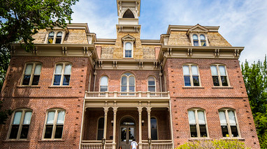 Exterior of Morrill Hall, an original building on the campus of the University of Nevada, Reno, a multi-story brick building with a large bell tower at the top of the building.
