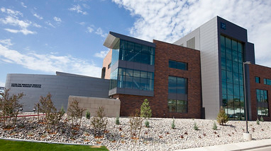Exterior of the William Pennington Health Sciences building, a modern brick and glass building with small trees and water-friendly landscaping in front of the building.