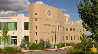 Exterior of the William and Myriam Pennington Medical Education building, a narrow yellow-brick building with large trees and a pathway in front of the building.