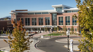 Exterior of the W.L Wiegand Fitness Center, a modern brick building with large bay windows, a circular entry way, trees and grass landscaping on the campus of the University of Nevada, Reno.