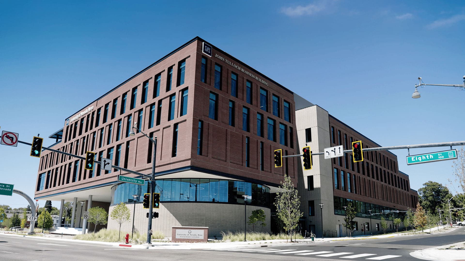 The John Tulloch Business Building, a modern, multi-story brick building with large windows located at the corner of University Drive and Eighth Street.